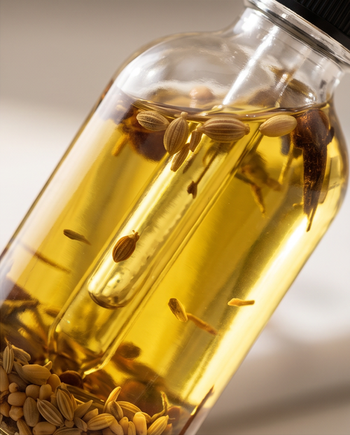 Glass bottle filled with oil and seeds on a neutral background
