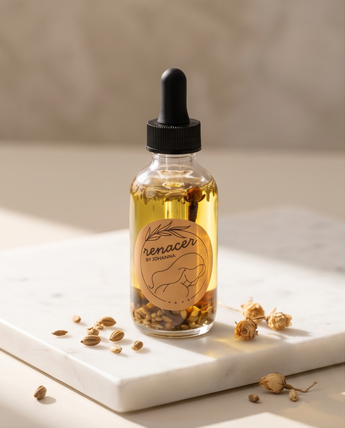 Glass bottle with a dropper labeled 'renacer' on a marble surface with dried herbs.